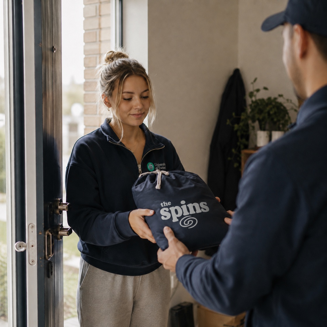 A student receiving a neatly packed The Spins laundry bag at her door